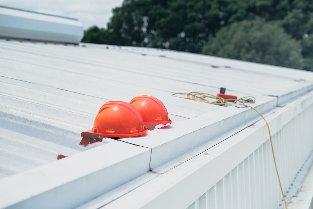 Red hard hats and safety equipment on a metal roof, emphasizing construction safety.